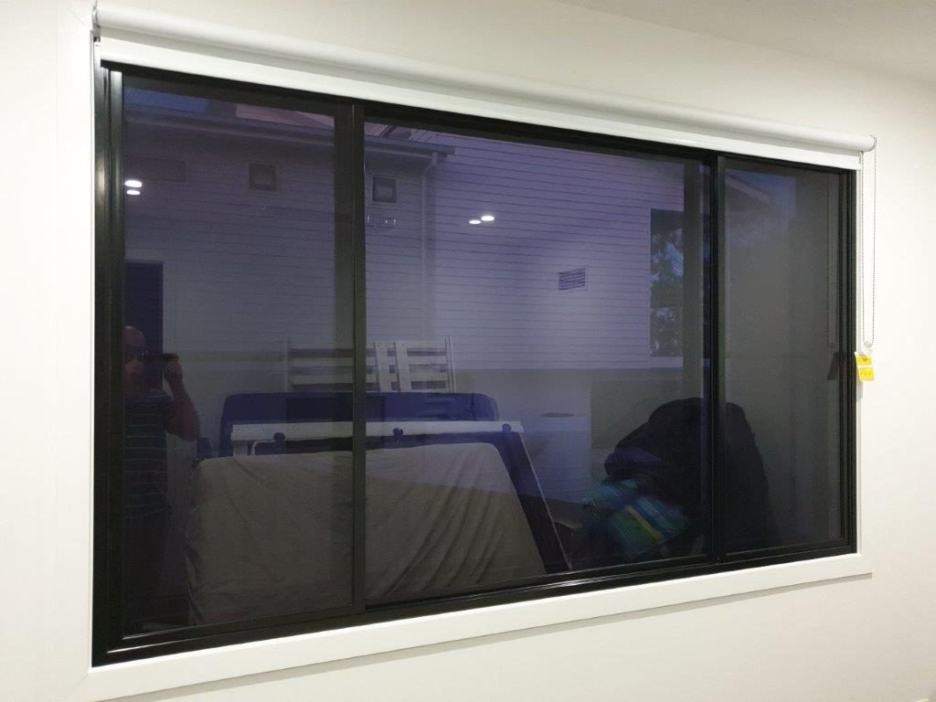 Secondary glazed acoustic windows with black frame in a bedroom with white walls