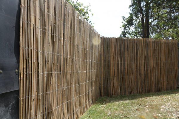 A bamboo fence wrap covering an acoustic fence wrap in a backyard